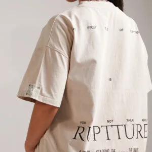 Vista trasera de camiseta color crema con estampado ‘RUPTTURE’.