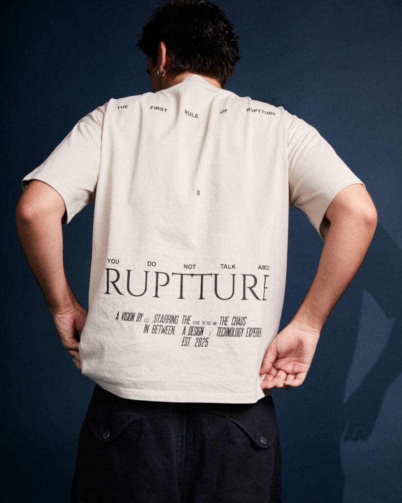 Modelo de espaldas luciendo la camiseta First Rule Tee con el manifiesto de ruptture, una apuesta por el streetwear sostenible.