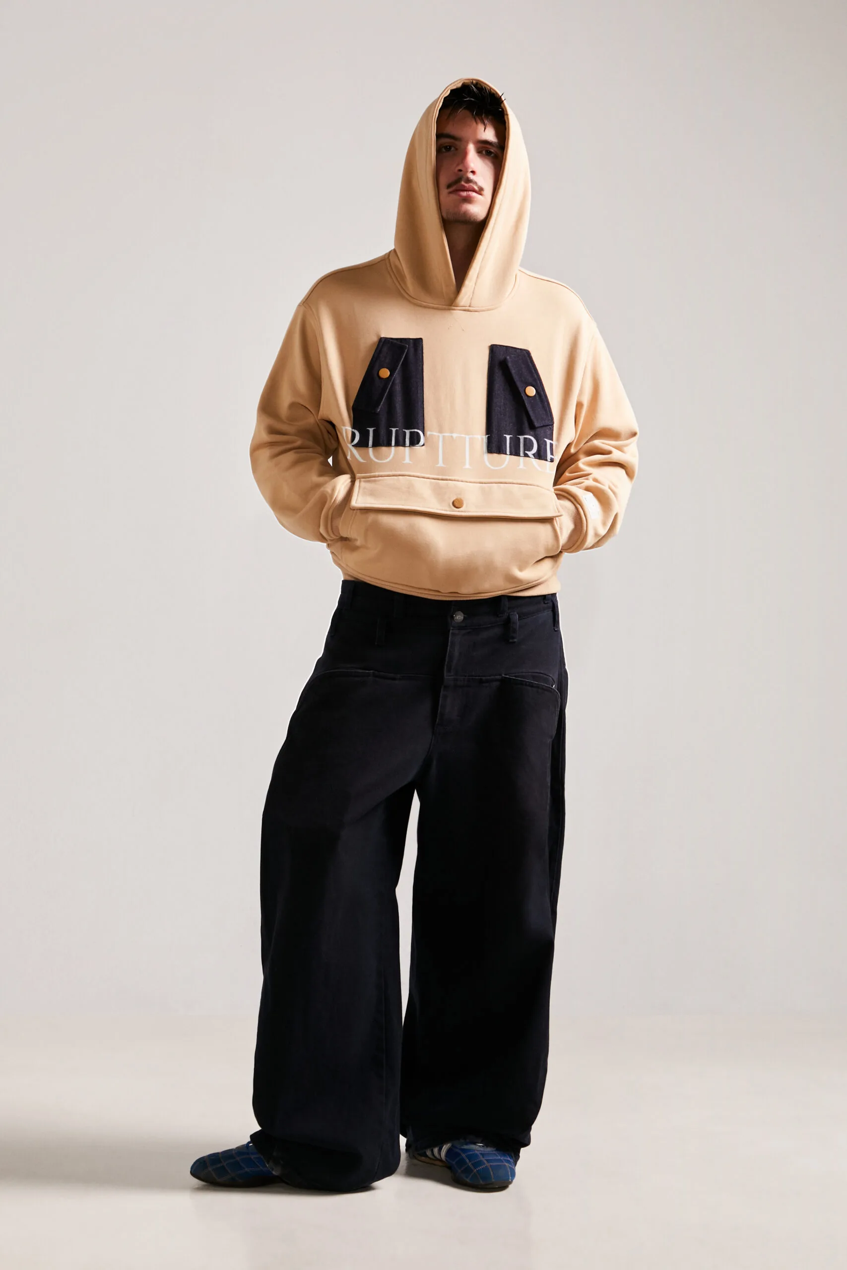 Modelo con sudadera streetwear unisex Utility Hoodie WORKSHIFT de bolsillos tácticos redefiniendo la moda streetwear.